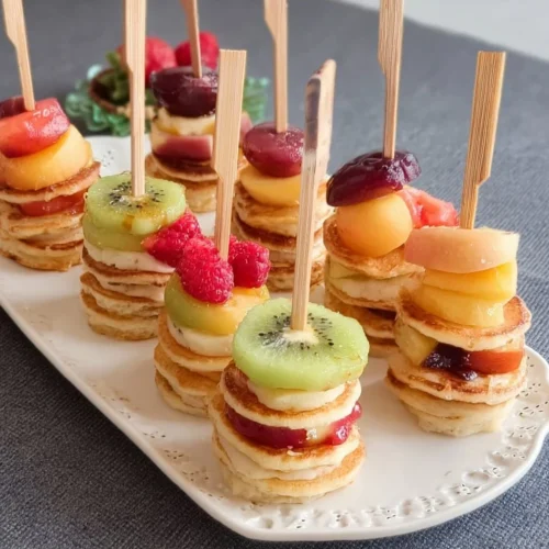 A plate of mini pancake stacks topped with syrup and berries.