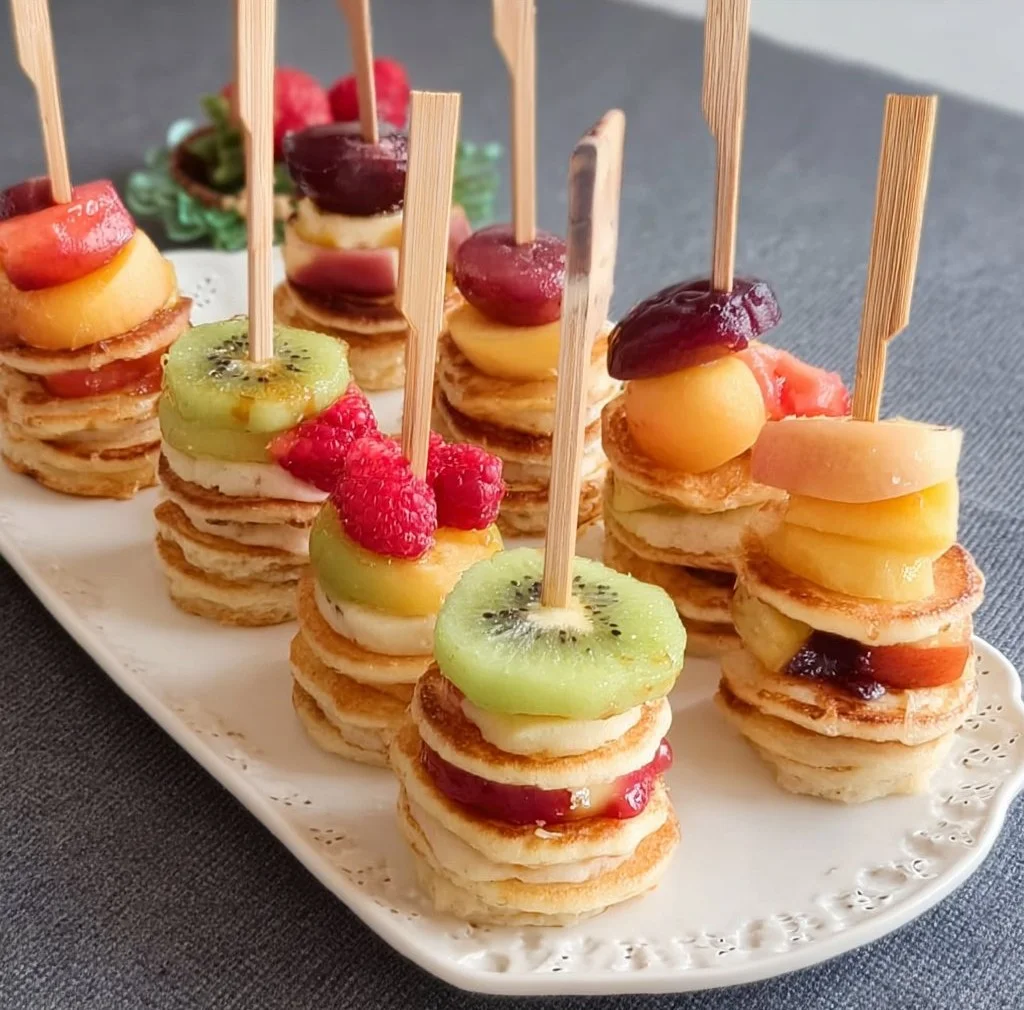 A plate of mini pancake stacks topped with syrup and berries.