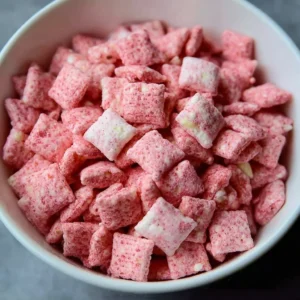 Delicious bowl of Strawberry White Chocolate Chex Mix featuring strawberries and white chocolate.