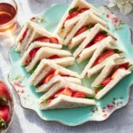 Strawberry tea sandwiches arranged on a plate for afternoon tea.